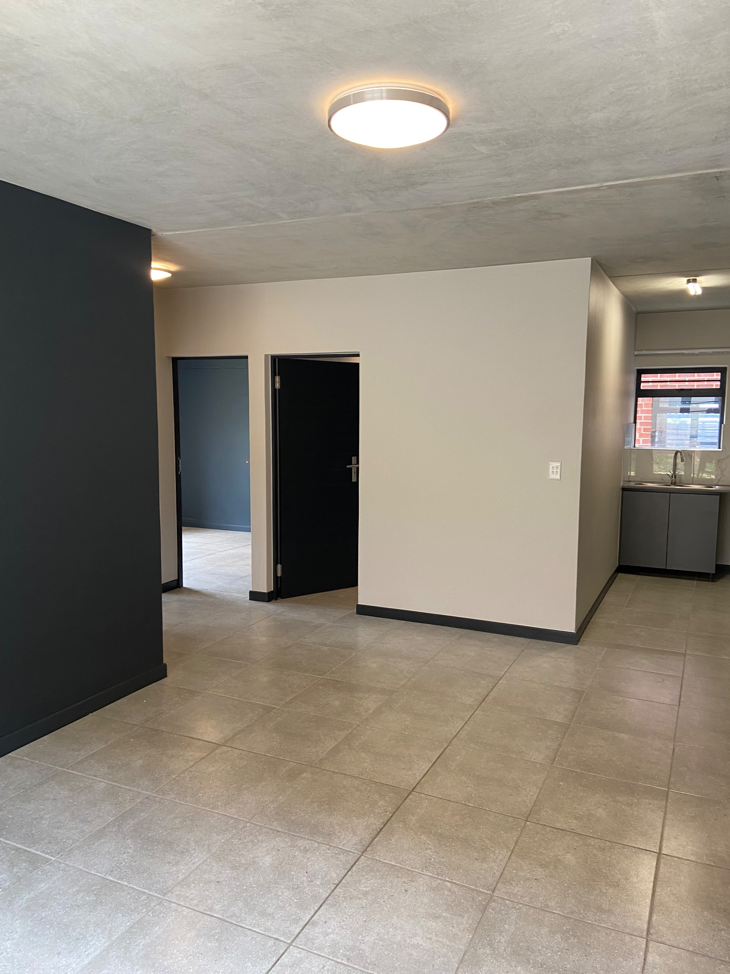 Open-plan living area of a Houss Rentals apartment with tiled floors and a fitted kitchen